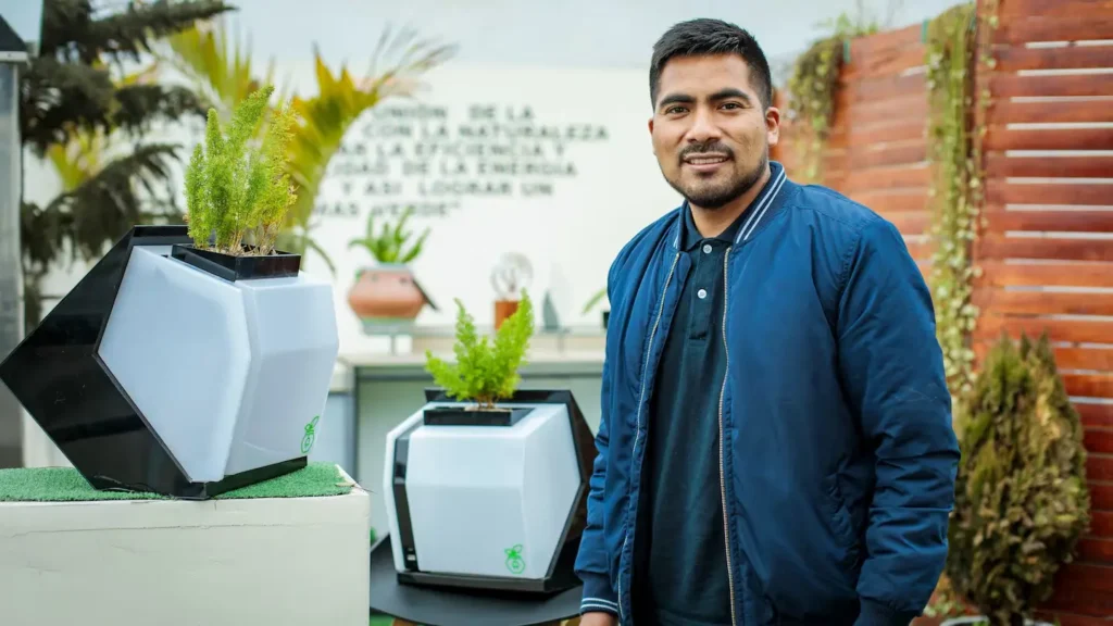 Hernán Asto sosteniendo el biocargador Alinti, dispositivo que genera energía eléctrica a partir de plantas