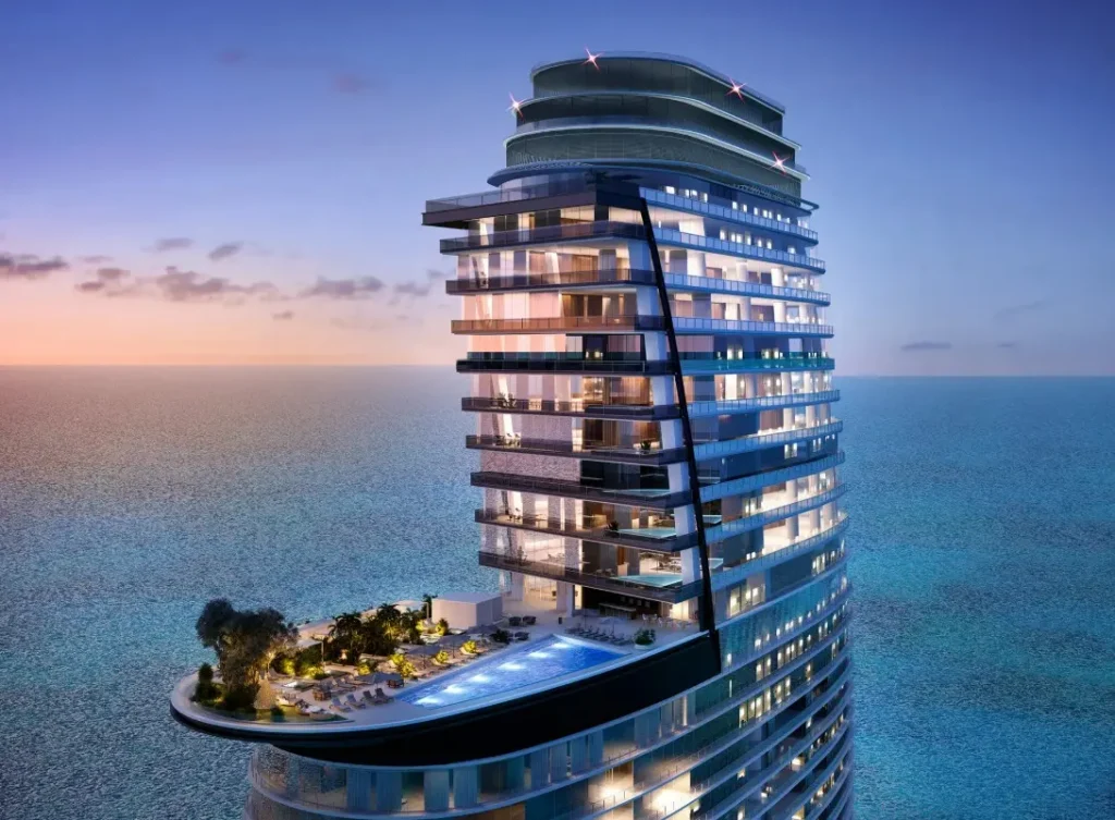 Vista nocturna del rascacielos Aston Martin Residences en Miami con piscina y fachada curva iluminada frente al océano