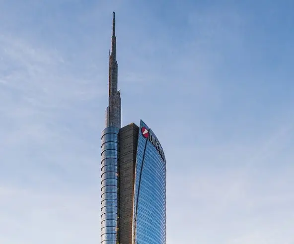 Fachada curvada de la Torre UniCredit con su pináculo iluminado, en Milán
