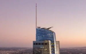 Vista de la parte superior del rascacielos Wilshire Grand Center en Los Ángeles, con su aguja LED y fachada de vidrio al atardecer