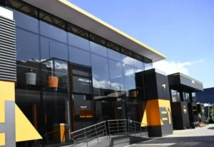 Motorhome del equipo McLaren de Fórmula 1 en el paddock de un circuito europeo, con diseño moderno, cristal templado y colores corporativos