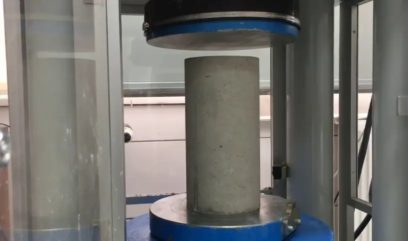 Máquina de ensayo de compresión aplicando carga a una probeta de hormigón