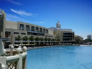 Vista panorámica del Dubai Mall con su fachada moderna y el lago artificial en primer plano