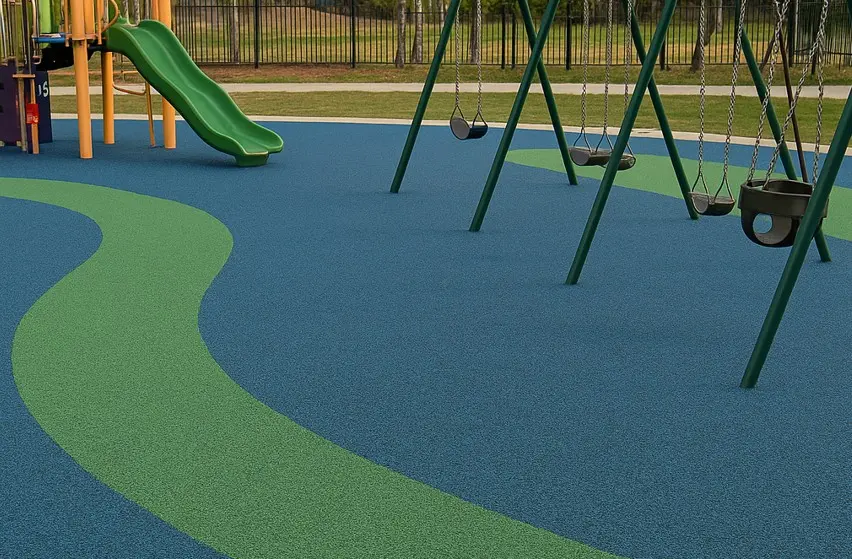 Pavimento de caucho reciclado azul y verde en un parque infantil con columpios y tobogán