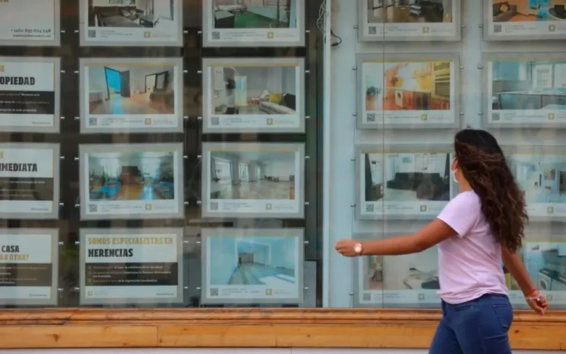 Mujer mirando escaparate inmobiliario relacionado con control del alquiler y oferta de viviendas