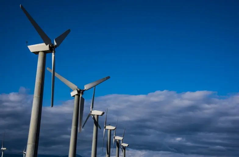 Aerogeneradores generando electricidad con energía eólica bajo un cielo azul y nubes