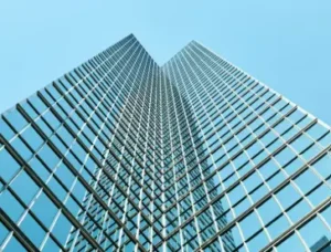 Fachada de vidrio laminado y estructura metálica reflejando el cielo en un edificio contemporáneo, símbolo de arquitectura sostenible y eficiente.