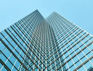 Fachada de vidrio laminado y estructura metálica reflejando el cielo en un edificio contemporáneo, símbolo de arquitectura sostenible y eficiente.