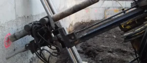 Equipo perforador realizando taladros inclinados para anclajes en un muro pantalla durante una excavación