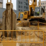 Excavación profunda de muro pantalla, con maquinaria pesada y uso de lodos bentoníticos para estabilizar el terreno