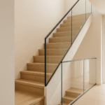 Escalera interior de vivienda con diseño moderno, peldaños de madera y barandilla de cristal sin montantes