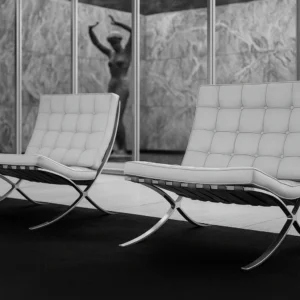 Silla Barcelona de Mies en un espacio arquitectónico que destaca su diseño moderno y los materiales originales del Pabellón de Barcelona