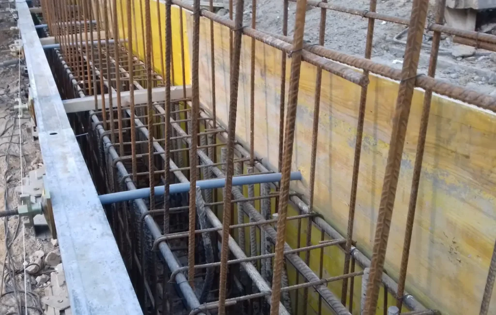 Armadura de una viga de coronación con encofrado lateral y barras de acero en un muro pantalla