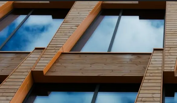 Fachada de edificio contemporáneo con estructura de madera vista y grandes superficies acristaladas